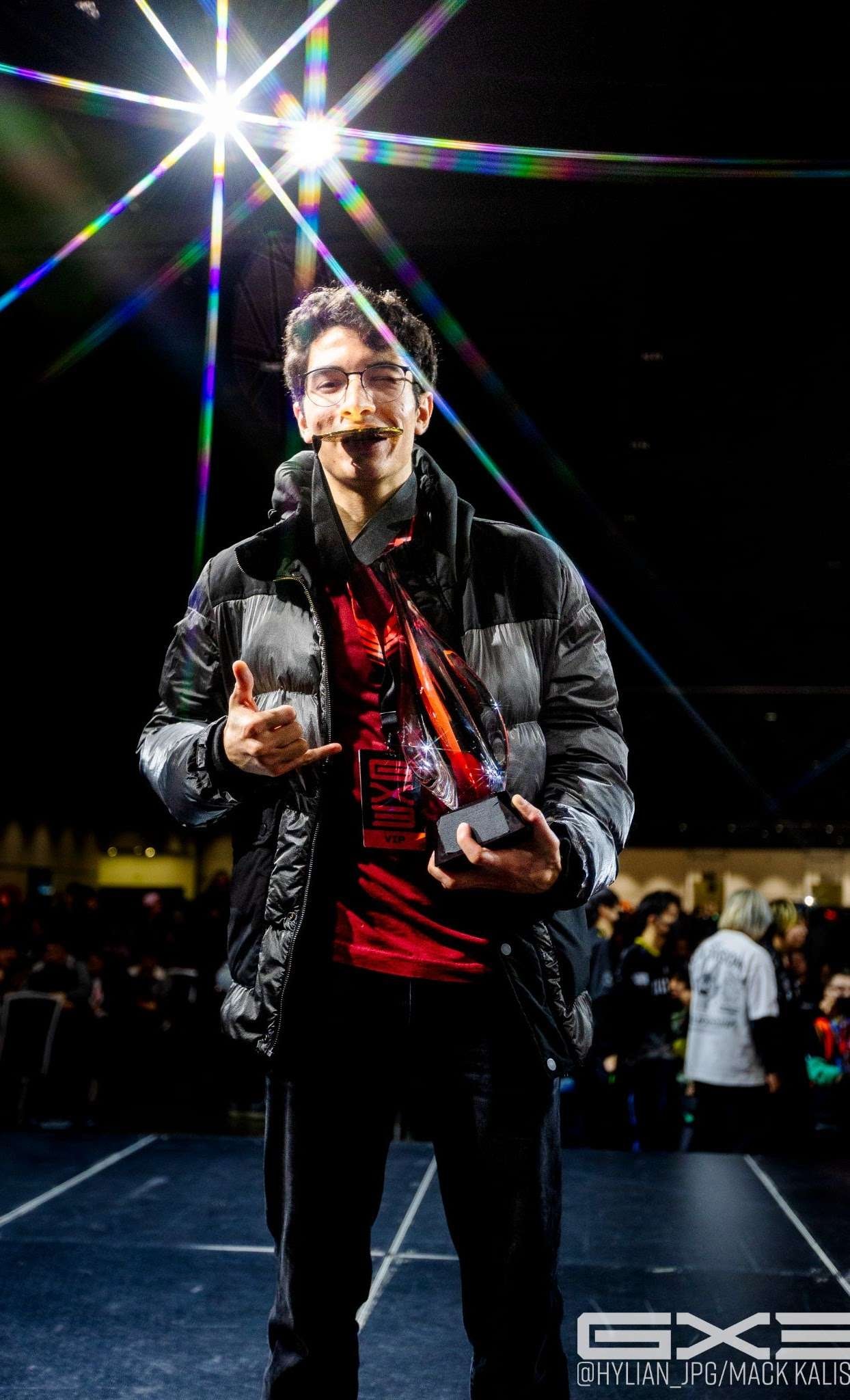 A GENESIS X3 competitor poses with a trophy beneath prismatic stage lights