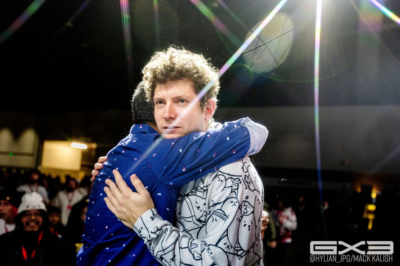 Two competitors embrace beneath the stage lights at GENESIS X3
